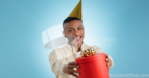 Image of Portrait, happy man and party hat with gift in studio for celebration mock up on blue background in Cape Town. Model, giveaway and present for birthday, prize or event with competition, deal or offer