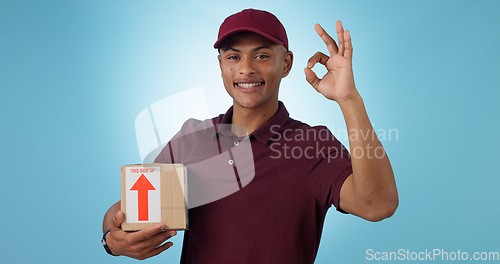 Image of Delivery man, box and okay hands for success, product excellence and courier services in studio. Happy portrait of supply chain worker or person with package for distribution on a blue background