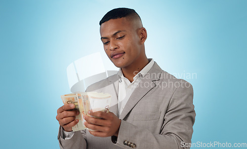 Image of Business man, cash and money for financial investment, budget and trading, profit or counting his savings in studio. Young trader with decision or doubt for income, loan or salary on blue background