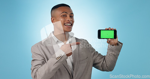 Image of Business man, phone green screen and pointing to presentation, sign up information or trading software in studio. Happy portrait of a young trader on mobile app, tracking markers and blue background