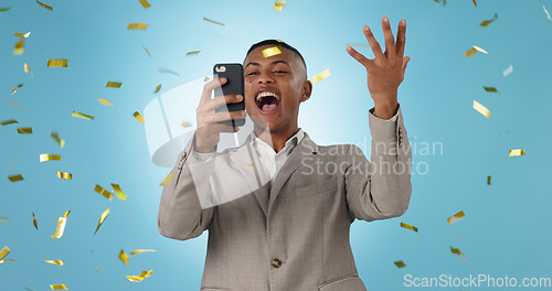 Image of Business man, phone and winning with confetti celebration, stock market news or competition winner in studio. Young trader in wow, surprise and excited for profit or sale on mobile on blue background