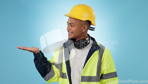 Image of Construction worker, smile and with hand for advertising, promotion or mockup in blue background. Happy, face and builder show safety announcement, presentation or choice with space in studio