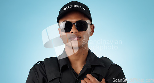 Image of Security guard, portrait and man in studio with glasses for surveillance, justice and law enforcement on blue background. Serious bodyguard for crime prevention, safety patrol and monitoring danger