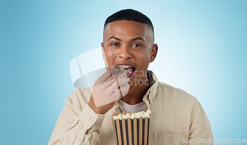 Image of Portrait, happy man and popcorn for cinema in studio on blue background for entertainment mockup. Male model, eating and hungry with delicious, snack and food for watching, television and theatre