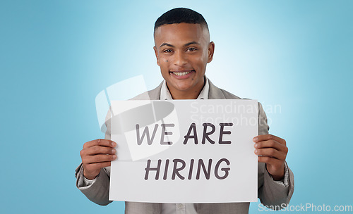 Image of Portrait, happy or businessman with we are hiring sign, work opportunity or vacancy advertising in studio. Smile, poster or manager with board text for job search or recruitment on blue background