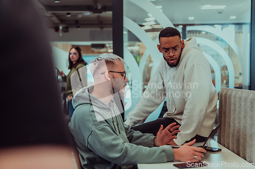 Image of Young group of business people brainstorming together in a startup space, discussing business projects, investments, and solving challenges.