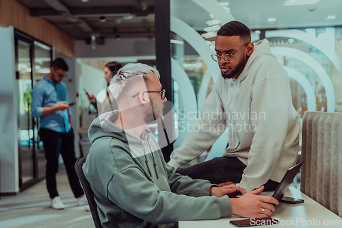 Image of Young group of business people brainstorming together in a startup space, discussing business projects, investments, and solving challenges.