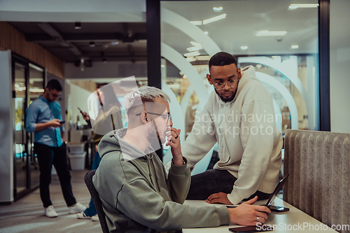 Image of Young group of business people brainstorming together in a startup space, discussing business projects, investments, and solving challenges.