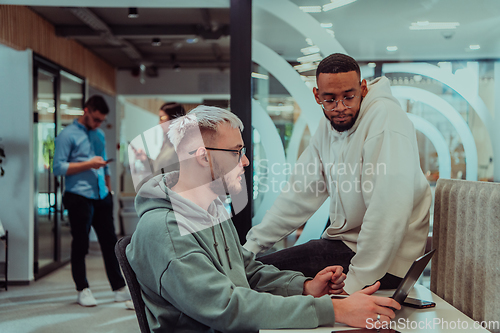 Image of Young group of business people brainstorming together in a startup space, discussing business projects, investments, and solving challenges.