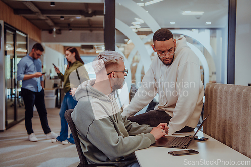 Image of Young group of business people brainstorming together in a startup space, discussing business projects, investments, and solving challenges.