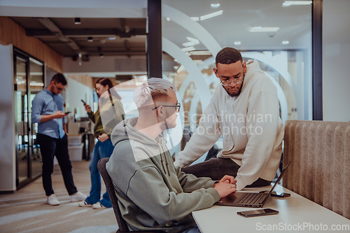 Image of Young group of business people brainstorming together in a startup space, discussing business projects, investments, and solving challenges.