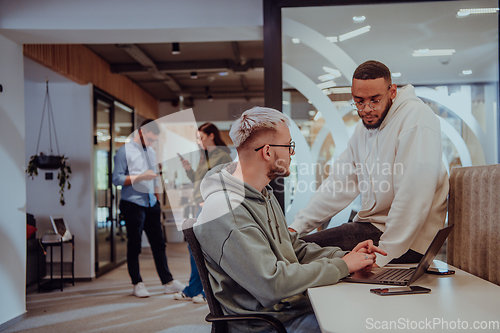 Image of Young group of business people brainstorming together in a startup space, discussing business projects, investments, and solving challenges.