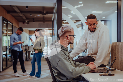 Image of Young group of business people brainstorming together in a startup space, discussing business projects, investments, and solving challenges.