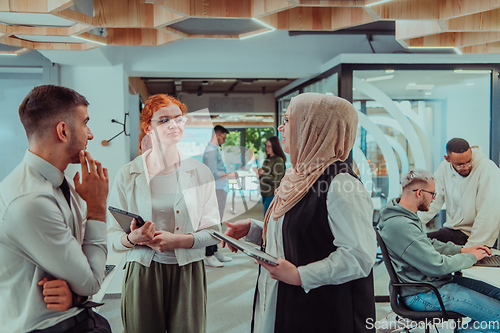 Image of Young group of business people brainstorming together in a startup space, discussing business projects, investments, and solving challenges.