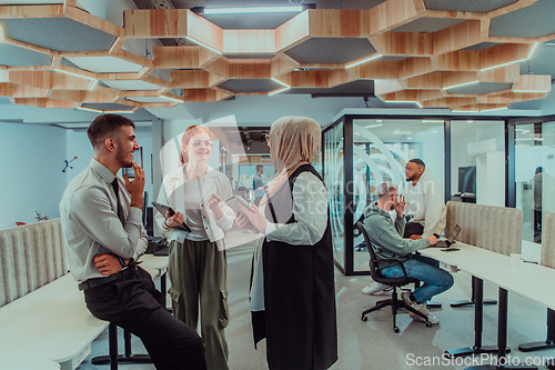 Image of Young group of business people brainstorming together in a startup space, discussing business projects, investments, and solving challenges.