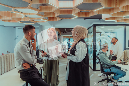 Image of Young group of business people brainstorming together in a startup space, discussing business projects, investments, and solving challenges.