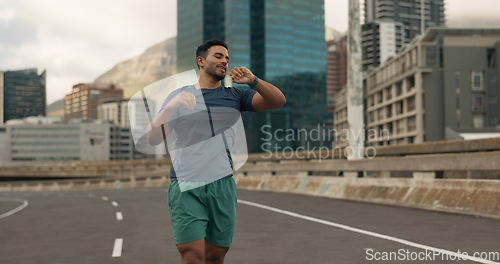 Image of Time, fitness and a man running in the city for sports training, getting ready for a marathon or race. Watch, exercise and a young runner or athlete outdoor in an urban town for his workout routine