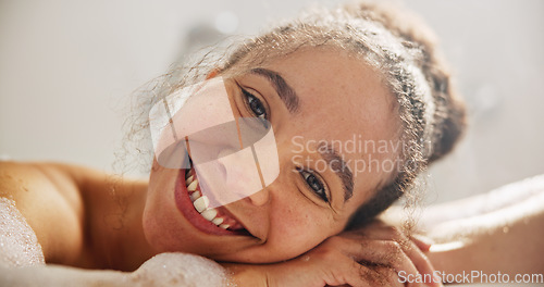 Image of Health, smile and face of a woman in the bath at her home for zen, calm or self care routine. Happy, peace and headshot portrait of young female person relaxing in a tub in the bathroom in apartment.