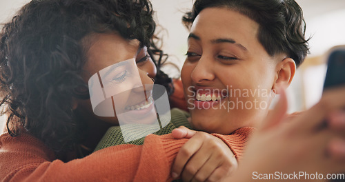 Image of Phone, hug and an lgbt couple laughing together in their home while browsing a social media app. Gay, love and comedy with happy lesbian women looking at memes on a mobile for fun or romantic bonding