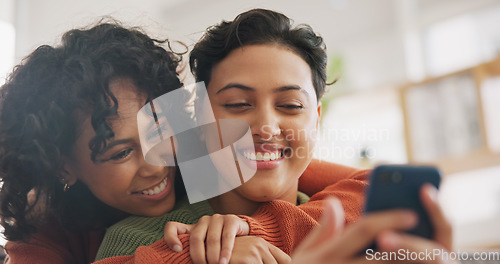 Image of Phone, hug and a gay couple laughing together in their home while browsing a social media app. LGBT, love and comedy with happy lesbian women looking at a meme on a mobile for fun, romance or bonding