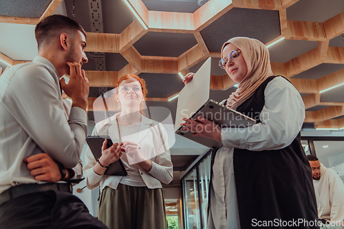 Image of Young group of business people brainstorming together in a startup space, discussing business projects, investments, and solving challenges.