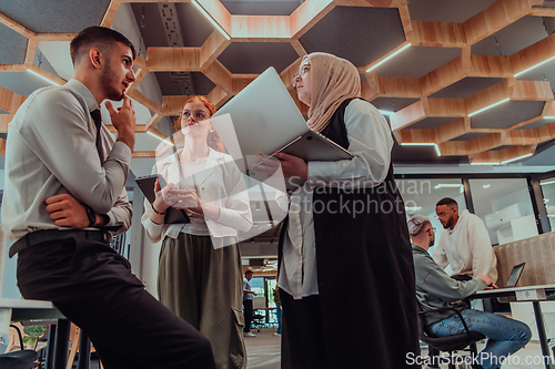 Image of Young group of business people brainstorming together in a startup space, discussing business projects, investments, and solving challenges.