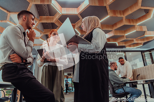 Image of Young group of business people brainstorming together in a startup space, discussing business projects, investments, and solving challenges.