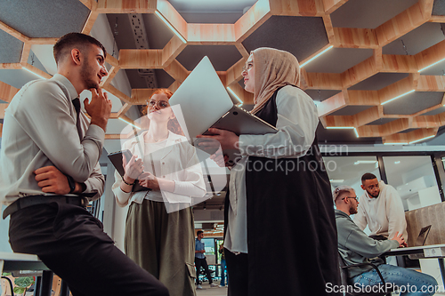 Image of Young group of business people brainstorming together in a startup space, discussing business projects, investments, and solving challenges.