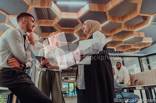 Image of Young group of business people brainstorming together in a startup space, discussing business projects, investments, and solving challenges.