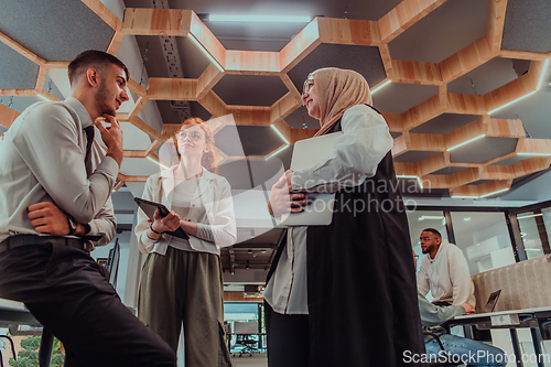 Image of Young group of business people brainstorming together in a startup space, discussing business projects, investments, and solving challenges.