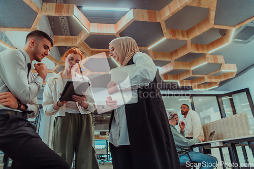 Image of Young group of business people brainstorming together in a startup space, discussing business projects, investments, and solving challenges.