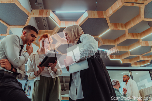 Image of Young group of business people brainstorming together in a startup space, discussing business projects, investments, and solving challenges.