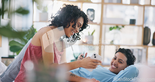 Image of Phone, lesbian couple and laughing at meme, social media or funny video in living room of their home. Lgbt, happy girls and bond with joke on smartphone while relaxing on sofa in lounge for happiness