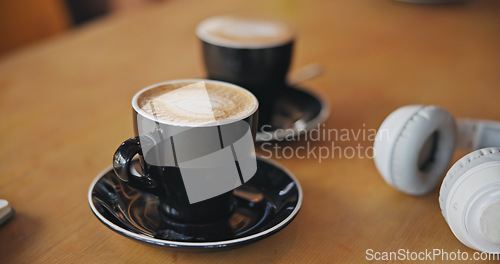 Image of Coffee, notebook and headphones on table, closeup and breakfast for cappuccino, drink and matcha in diner. Cafe, restaurant and mug for latte, espresso and book with audio tech in morning in shop