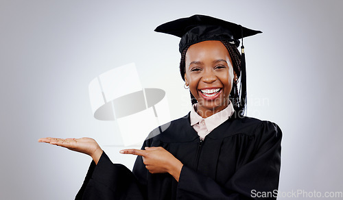 Image of Graduation, space or portrait of student pointing to education, college or university offer. Smile, black woman or happy graduate in studio for scholarship, promotion or mockup on grey background