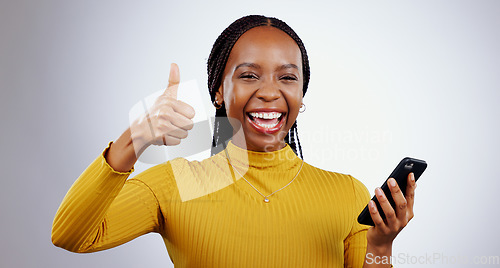 Image of Phone, thumbs up and portrait of happy black woman in studio with review, feedback or vote on grey background. Success, emoji and face of lady model with thank you sign for smartphone, app or support