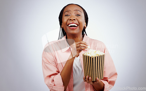 Image of Portrait, laughing or black woman watching a movie in studio for cinema with popcorn to relax. Comedy, funny or happy African person eating snack for streaming film or subscription on grey background