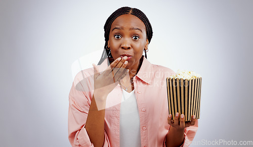Image of Portrait, surprise or black woman watching movie in studio for cinema with popcorn to relax. Omg, wow or shocked African person eating snack for streaming film or subscription on grey background