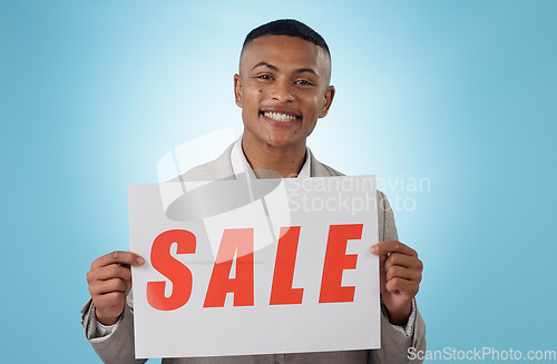 Image of Portrait, sale sign or businessman by offer, discount deal or launch for poster advertising in studio. Happy, smile or manager with board for message, marketing or promotion card on blue background