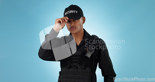 Image of Security guard, confidence and man or employee in a studio with police and law enforcement. Blue background, surveillance and officer with hat and helping for safety and danger of bodyguard worker