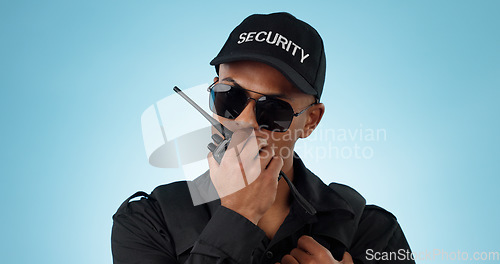 Image of Security, radio and an officer man on a blue background in studio for surveillance or communication. Face, uniform and sunglasses with a young law person speaking on a walkie talkie for patrol