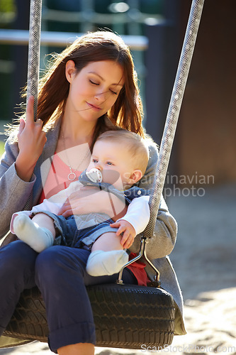 Image of Woman, baby and swing on park for play, bonding and love with sunshine, child development and care. Mother, kid and infant swinging outdoor in summer for fun, enjoyment and nurture with happiness