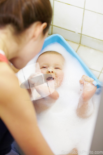 Image of Baby, mother or play in bathtub for shower, cleaning and hygiene with foam or bubbles for bonding. Child, woman or washing infant in bathroom of home for parenting, development and love with water