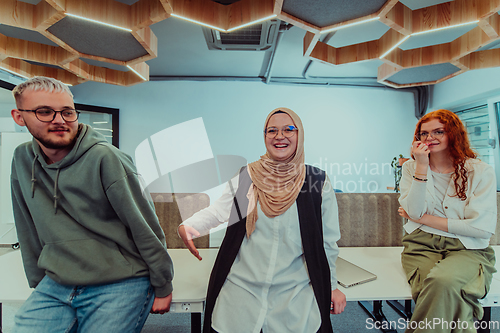 Image of A group of young business professionals stands together, taking a well-deserved break from their busy workday, showcasing camaraderie, teamwork, and a moment of relaxation in their dynamic workplace