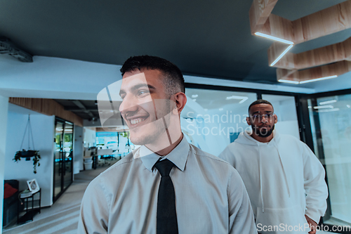 Image of A group of young business professionals stands together, taking a well-deserved break from their busy workday, showcasing camaraderie, teamwork, and a moment of relaxation in their dynamic workplace