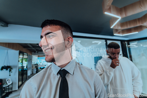 Image of A group of young business professionals stands together, taking a well-deserved break from their busy workday, showcasing camaraderie, teamwork, and a moment of relaxation in their dynamic workplace