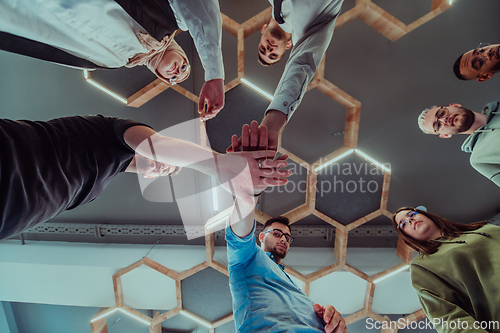 Image of A group of young businessmen offer their hands together, symbolizing togetherness in the business world