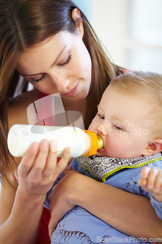 Image of Mother, baby and holding with bottle in home of formula, feeding or hunger for future growth. Woman, infant or son with nutrition for child development, milestone and health in kitchen with bonding