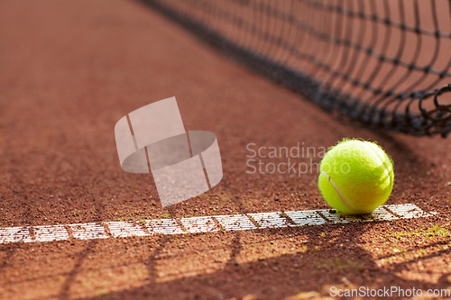 Image of Tennis, ball and clay court, net and line for exercise, training and fitness outdoor in summer. Sports, netting and closeup of sphere on ground for game, competition and workout on field and pitch