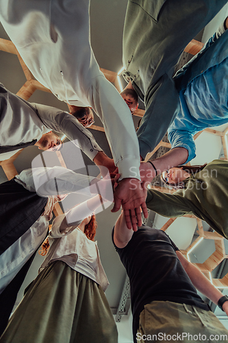 Image of A group of young businessmen offer their hands together, symbolizing togetherness in the business world